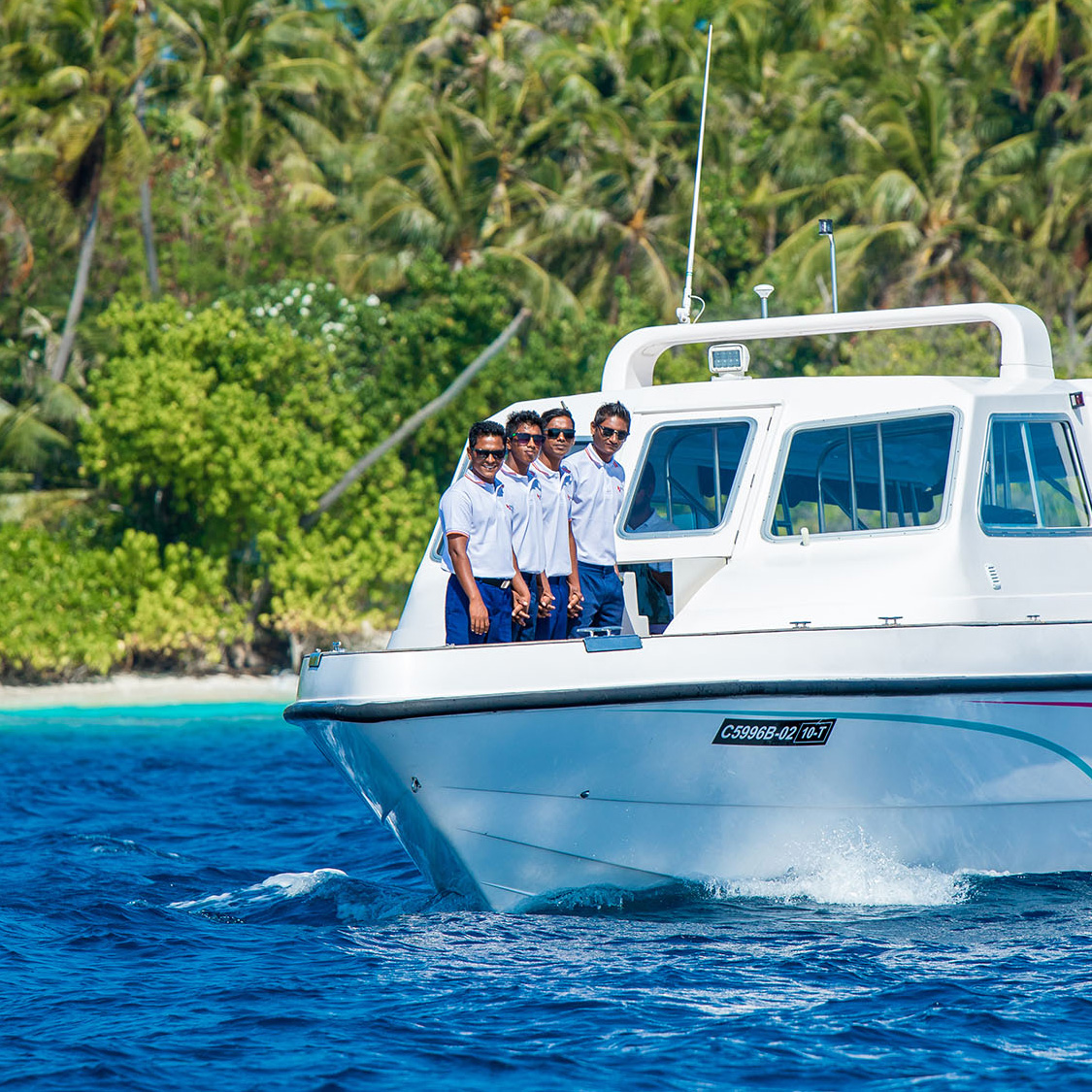 Four uniformed crew members standing on the bow of an Arriva speedboat, highlighting the professional service of Arriva Maldives Speedboat Transfer Company.